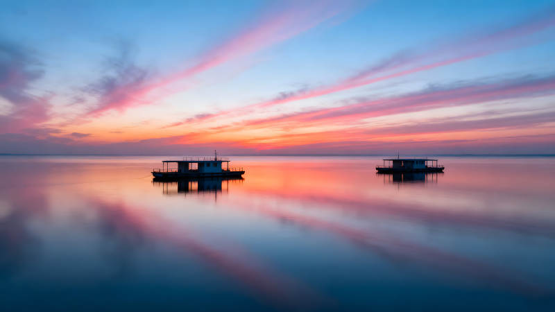 夕陽下水面平靜的小船-圖片