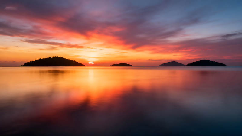 夕阳下的岛屿倒影宁静而壮丽-图片