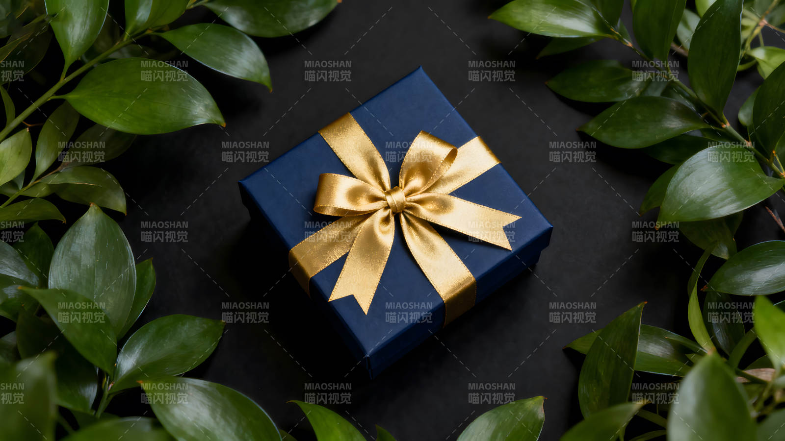 蓝色礼盒配金色蝴蝶结与绿叶-图片