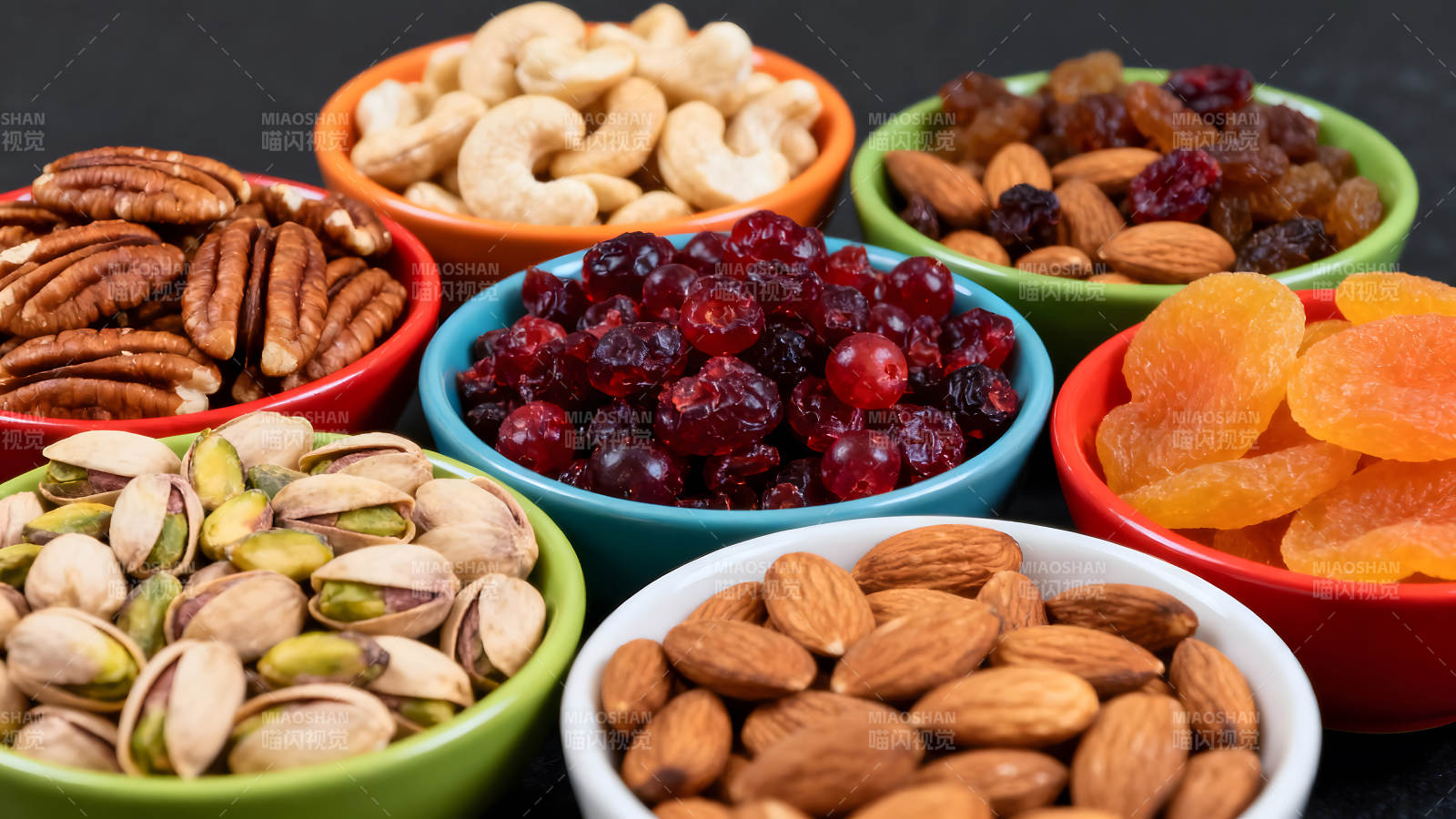 各種堅果和干果盛放在彩色的碗中-圖片