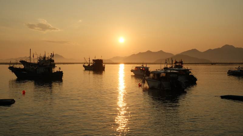 夕阳下的渔船剪影图片