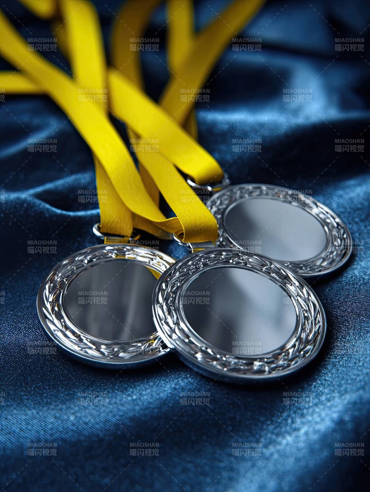 三枚奖牌静置于蓝色布料之上图片