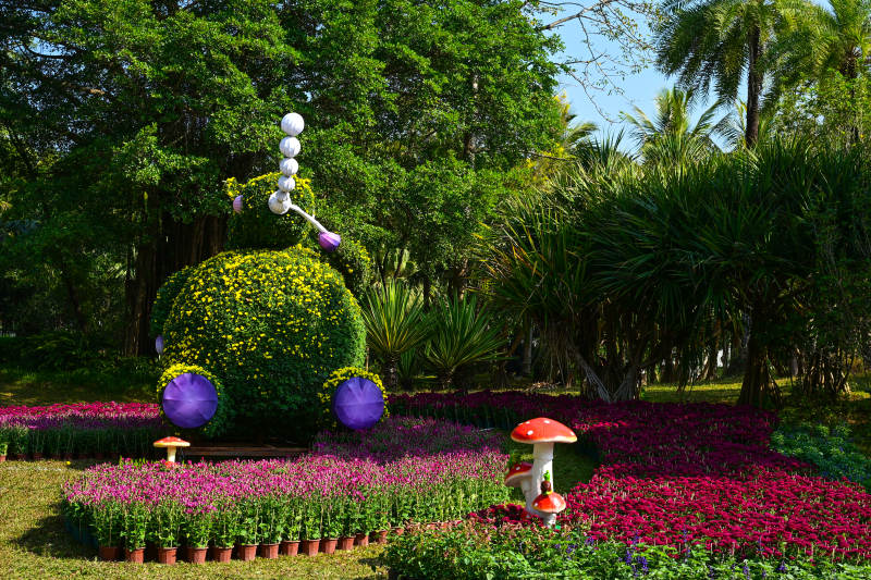 花海中的红色蘑菇雕塑与植物造型图片