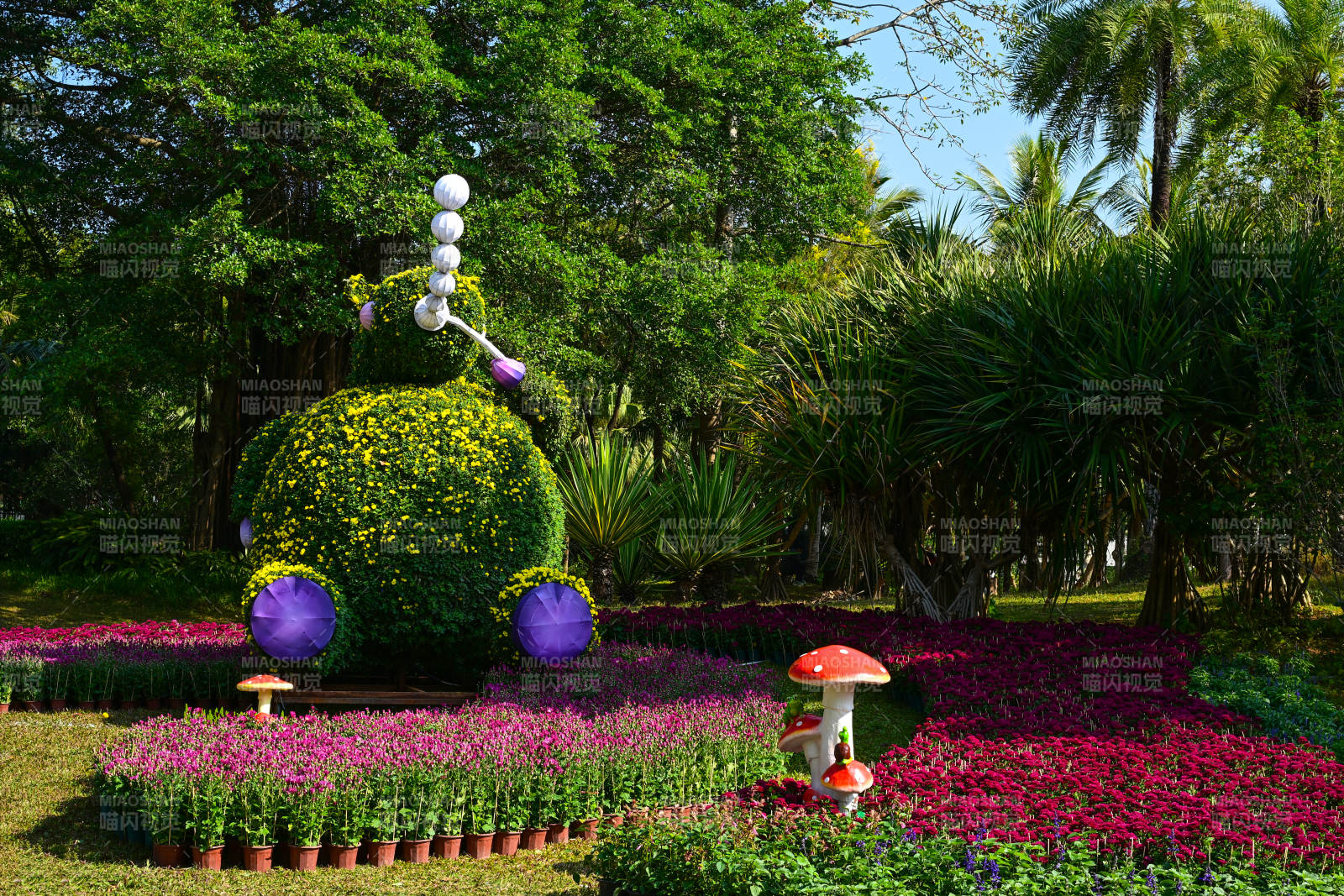 花海中的红色蘑菇雕塑与植物造型图片