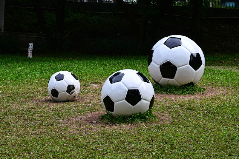 户外草坪上大小不一的三个足球雕塑艺术图片