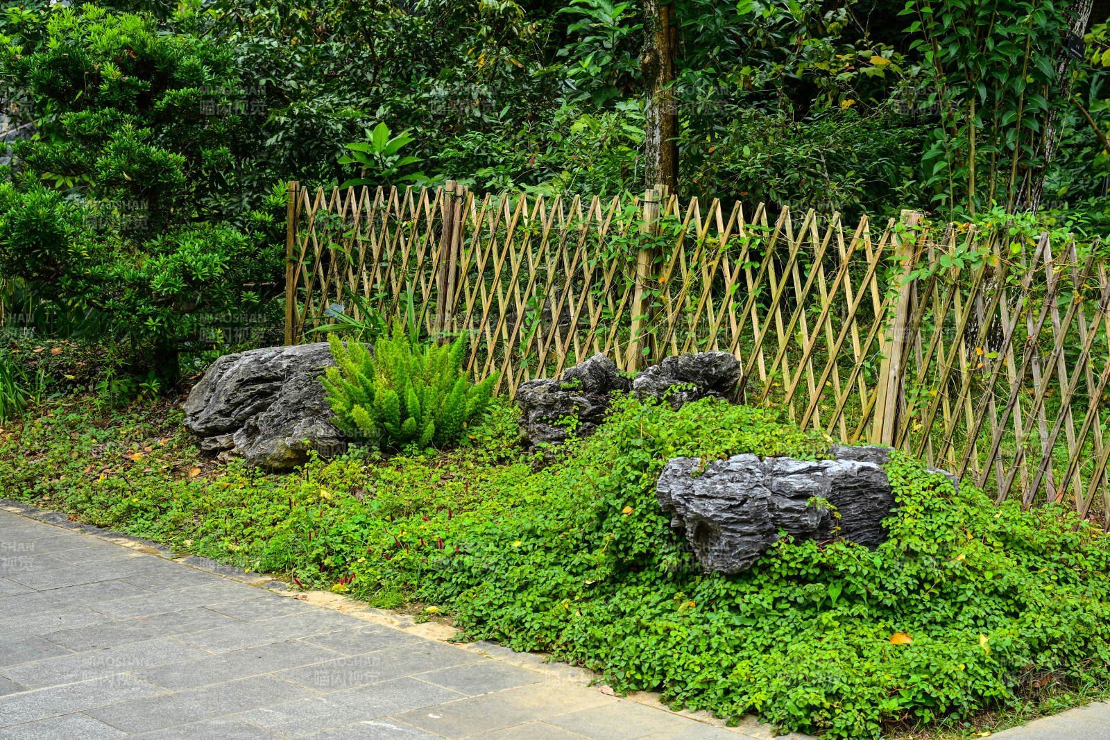 路边竹篱笆旁绿植与石头景观图片