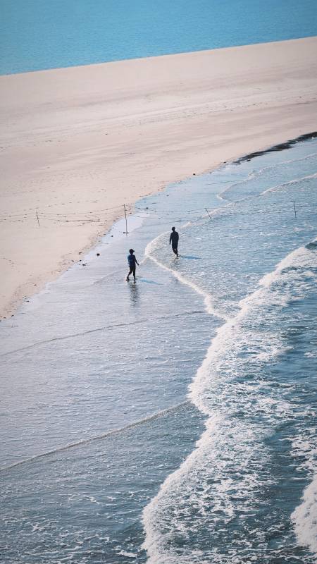泉州海边散步的两人图片