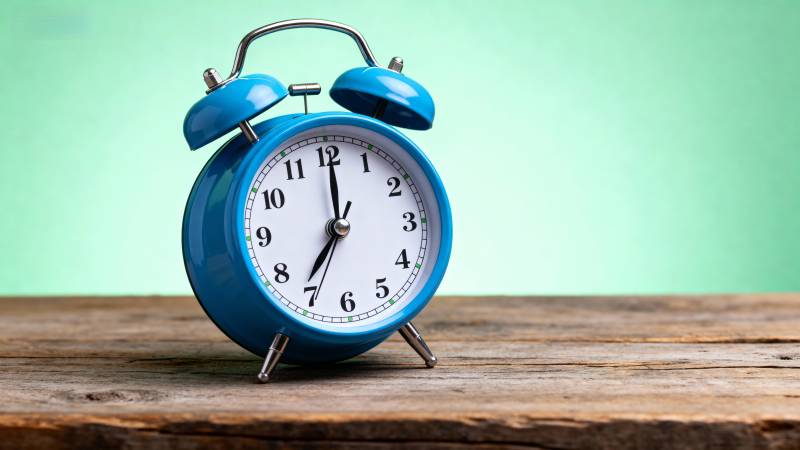 蓝色闹钟静置木桌图片