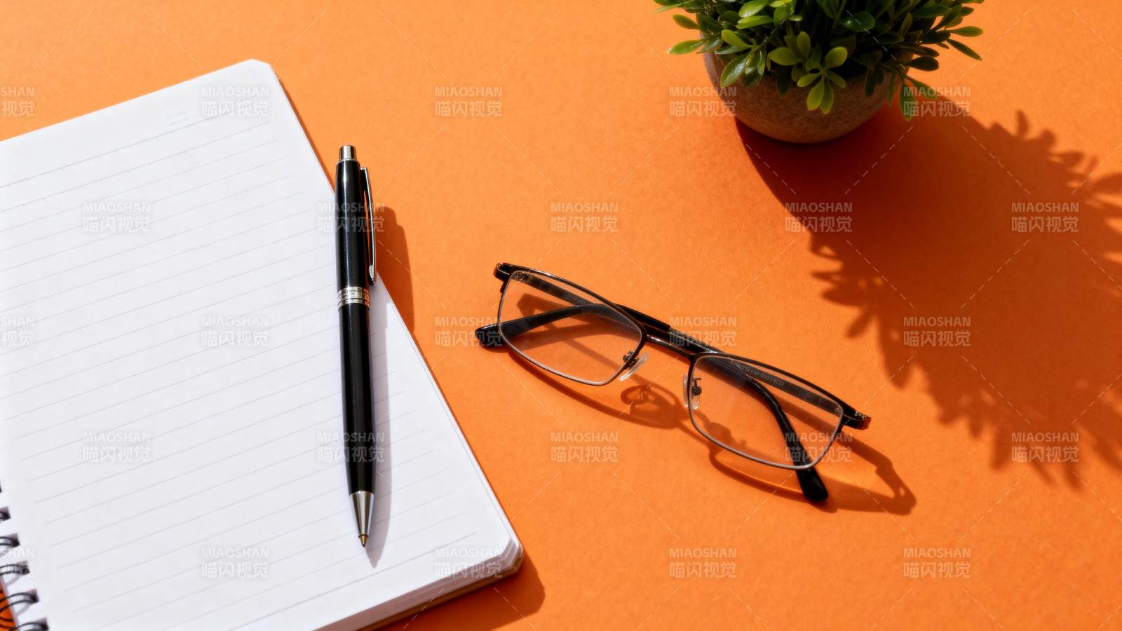 橙色桌面上的文具与眼镜图片