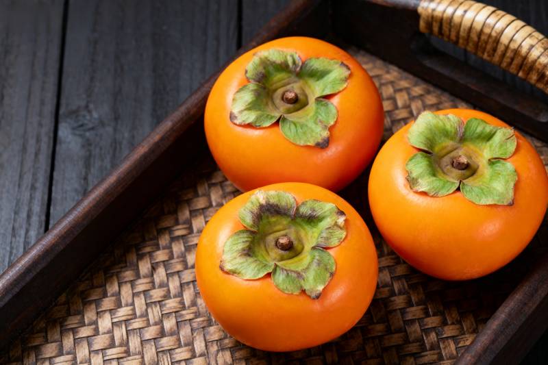 三颗柿子静置于竹篮图片