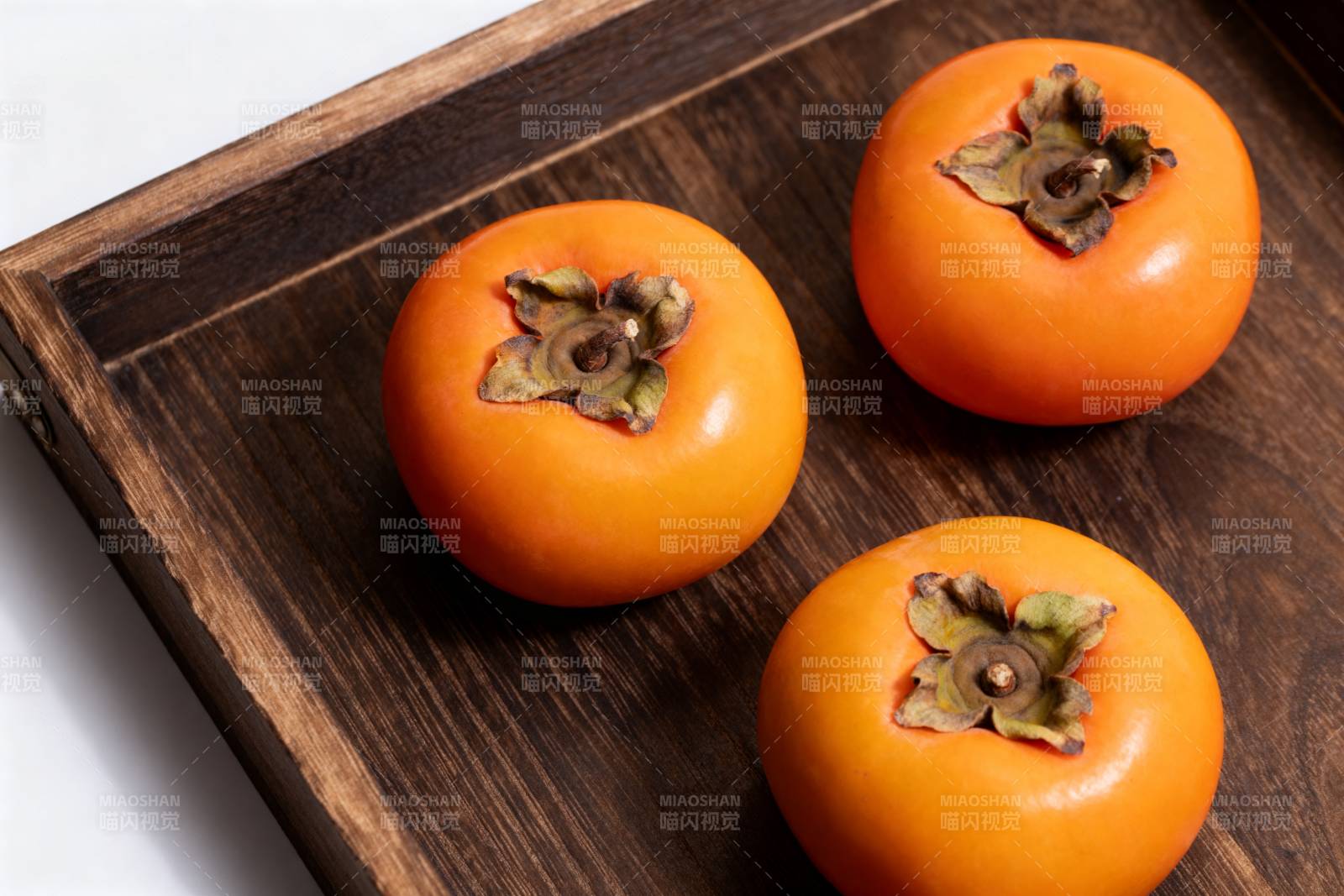 三颗柿子静置木盘图片