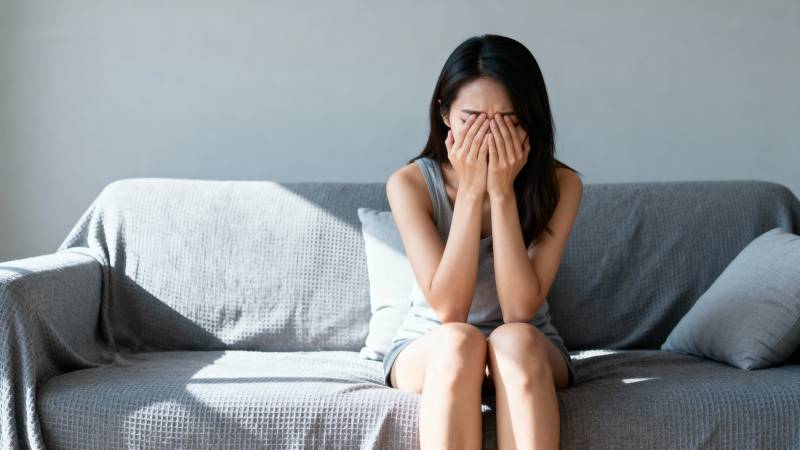 女子掩面坐在沙发上图片