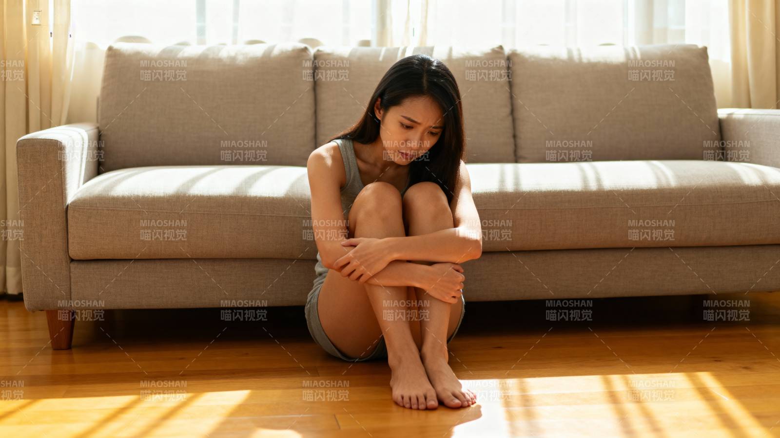 女子蜷坐地板沉思图片