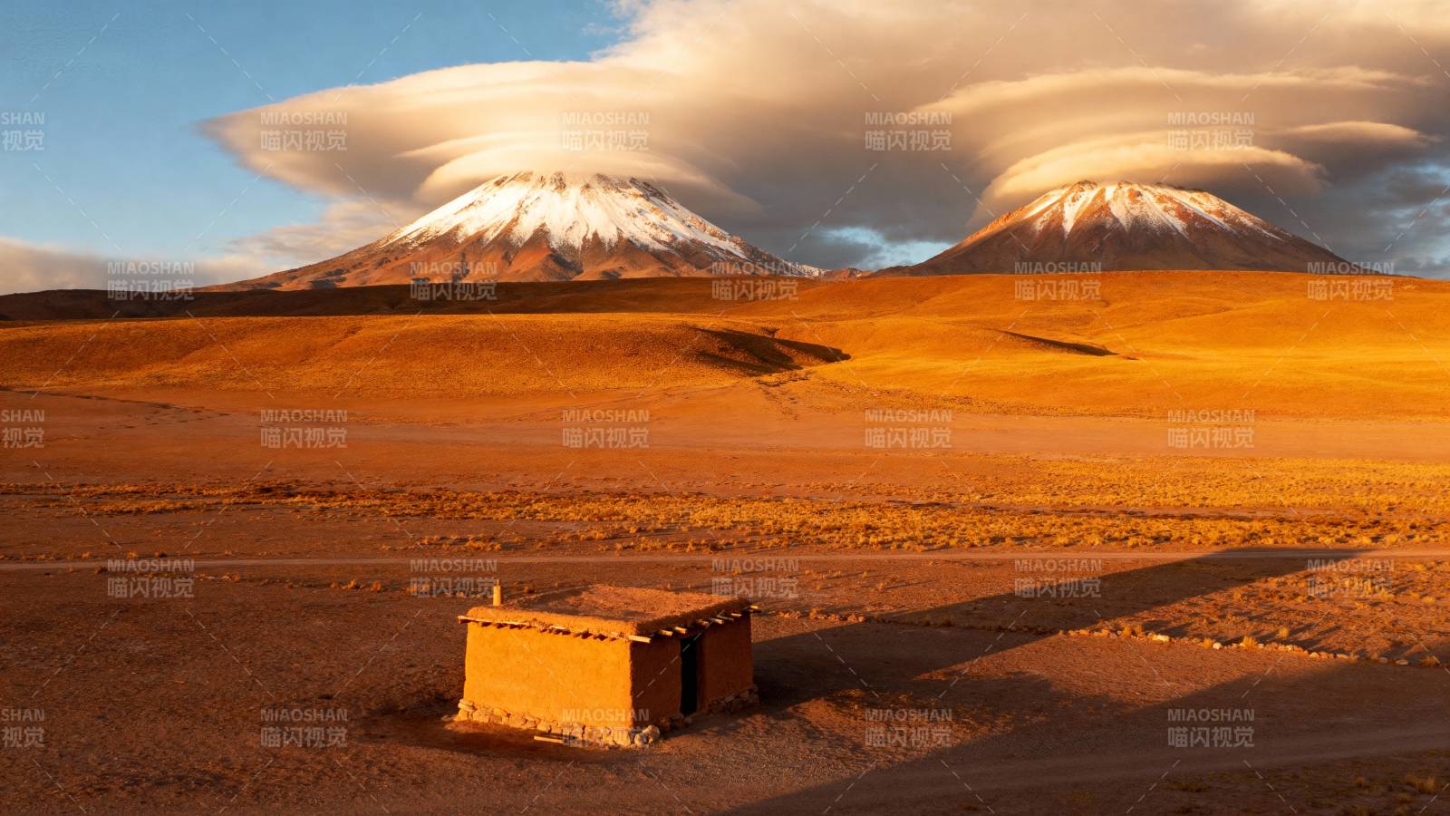 沙漠中的孤屋与雪山图片