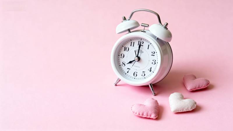 粉色背景上的闹钟与爱心图片