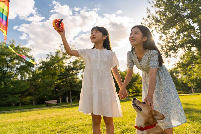 母女公园放风筝与宠物狗图片