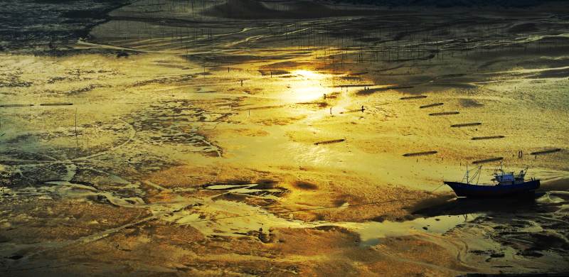 夕阳下的滩涂渔船图片