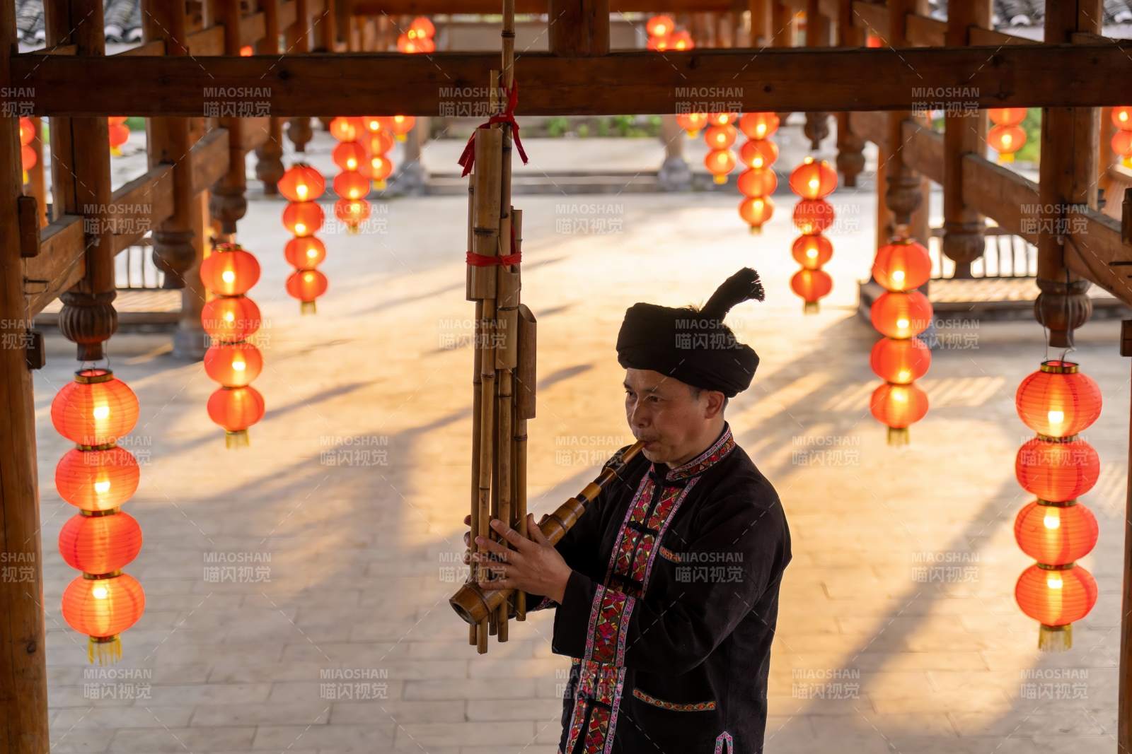 身着民族服饰男子吹奏竹管乐器图片