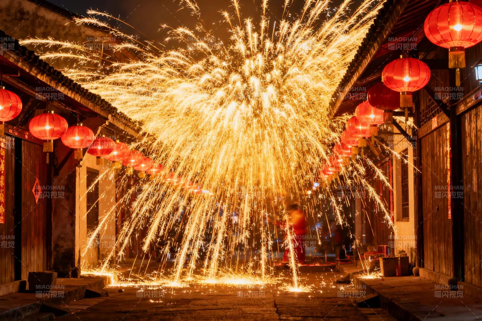 古巷夜空烟花绽放灯笼高挂图片