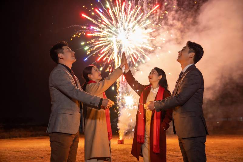 四人夜空烟花下击掌庆祝图片