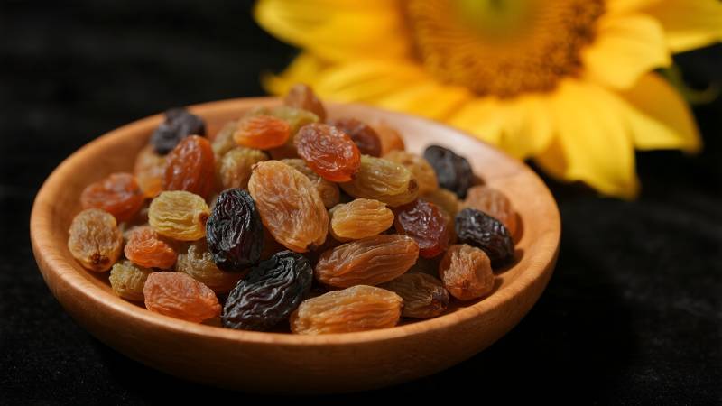 木碗葡萄干与向日葵图片